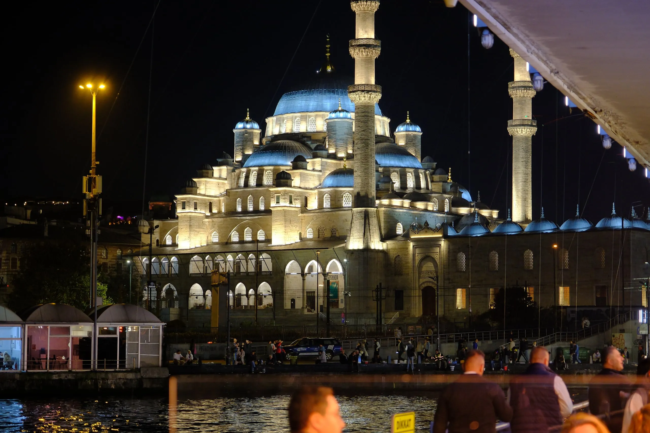 The New Mosque (Yeni Cami) lit up at night, seen from the restaurant’s tables under the bridge