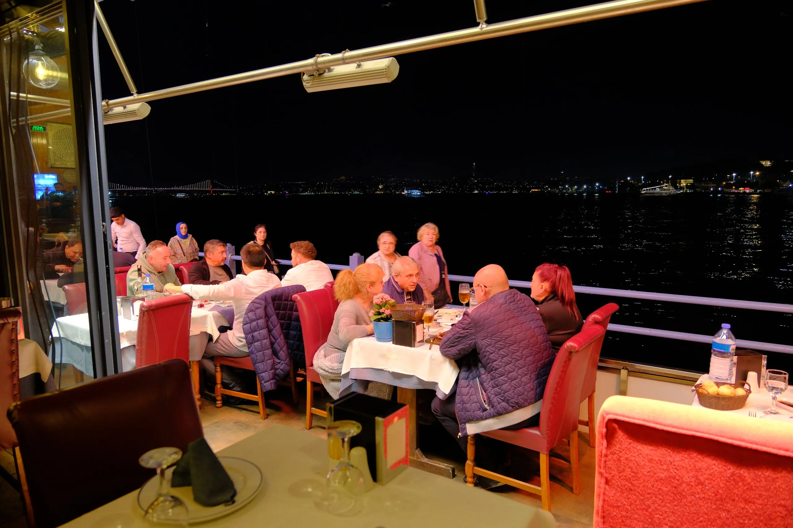 Open-air waterfront tables along the Galata Bridge in the evening